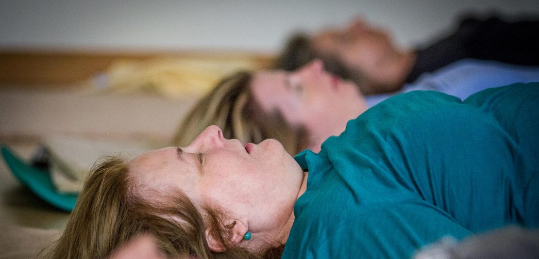 Personen liegen am Rücken auf Matte bei Feldenkrais-Kurs in Seminarraum